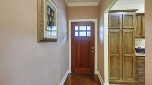 Un pasillo con una puerta de madera, un cuadro enmarcado en la pared y armarios de madera.