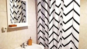 A bathroom with a white sink, a mirror, and a black and white chevron shower curtain. - Casa da Travessa (Horta)
