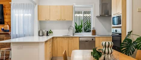 Una cucina moderna con mobili in legno, un'isola centrale e un'area pranzo con tavolo e sedie.