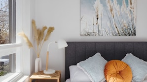 A bedroom with a bed, bedside table, lamp, and a wall-mounted painting. - Cocomo Stylish Pet Friendly Elwood Apartment (Elwood)