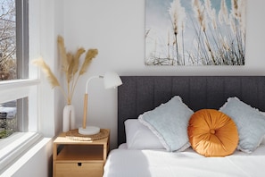 A bedroom with a bed, bedside table, lamp, and a wall-mounted painting. - Cocomo Stylish Pet Friendly Elwood Apartment (Elwood)