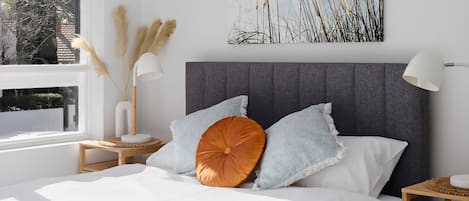 Una camera da letto con un letto, un comodino, una lampada e una finestra vista alberi.