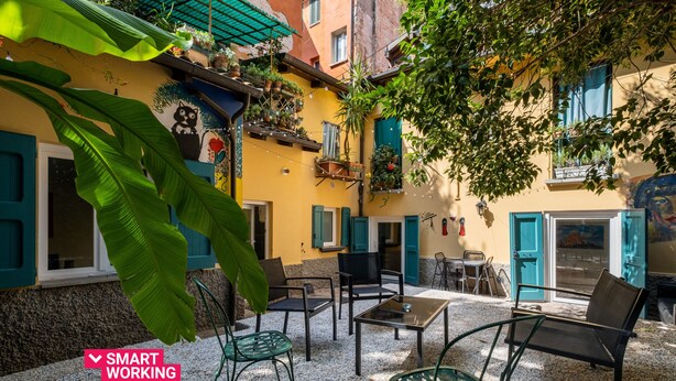 Une cour avec des sièges en plein air, une fresque murale et des plantes en pot.