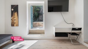 Une chambre moderne avec un lit, un bureau et une chaise, une télévision et un tableau.
