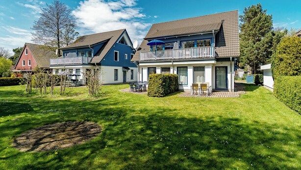 A row of two-story houses with a well-maintained lawn and a small garden area. - Apartment for up to 4 people,central,quiet,south-facing terrace,sauna,WLAN,bicycle shed,parking lot (Prerow)