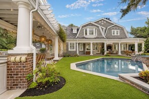 Una casa con piscina, un portico coperto e un camino in pietra.