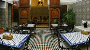 Un interior tradicional marroquí con un arco central, baldosas con diseños y muebles de madera.
