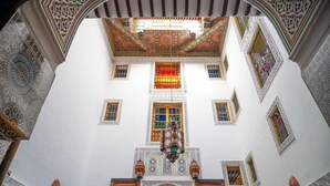 Una habitación con techo alto, intrincados trabajos de azulejos y una puerta de madera en la parte inferior.