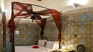 Una habitación con cama con dosel, paredes con diseño y una lámpara decorativa.