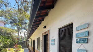 A building with a tiled walkway, potted plants, and multiple doors. - Pousada Bahan (Ubatuba)