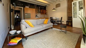 A modern living room with a grey sofa, a dining table, and a kitchen area in the background. - A view on Brescia's rooftops (Brescia)