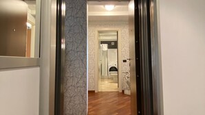 A hallway with a wooden floor leading to a bathroom with a toilet and a shower. - A view on Brescia's rooftops (Brescia)