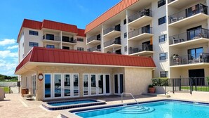 A multi-story building with a swimming pool and outdoor seating area. - 107 - 2/2 Poolside Ocean View (New Smyrna Beach)