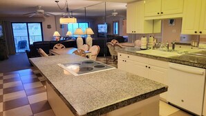 A modern kitchen with granite countertops, a built-in stove, and white cabinetry. - 107 - 2/2 Poolside Ocean View (New Smyrna Beach)