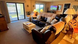 A living room with a sofa, a coffee table, a TV, and a chair. - 107 - 2/2 Poolside Ocean View (New Smyrna Beach)