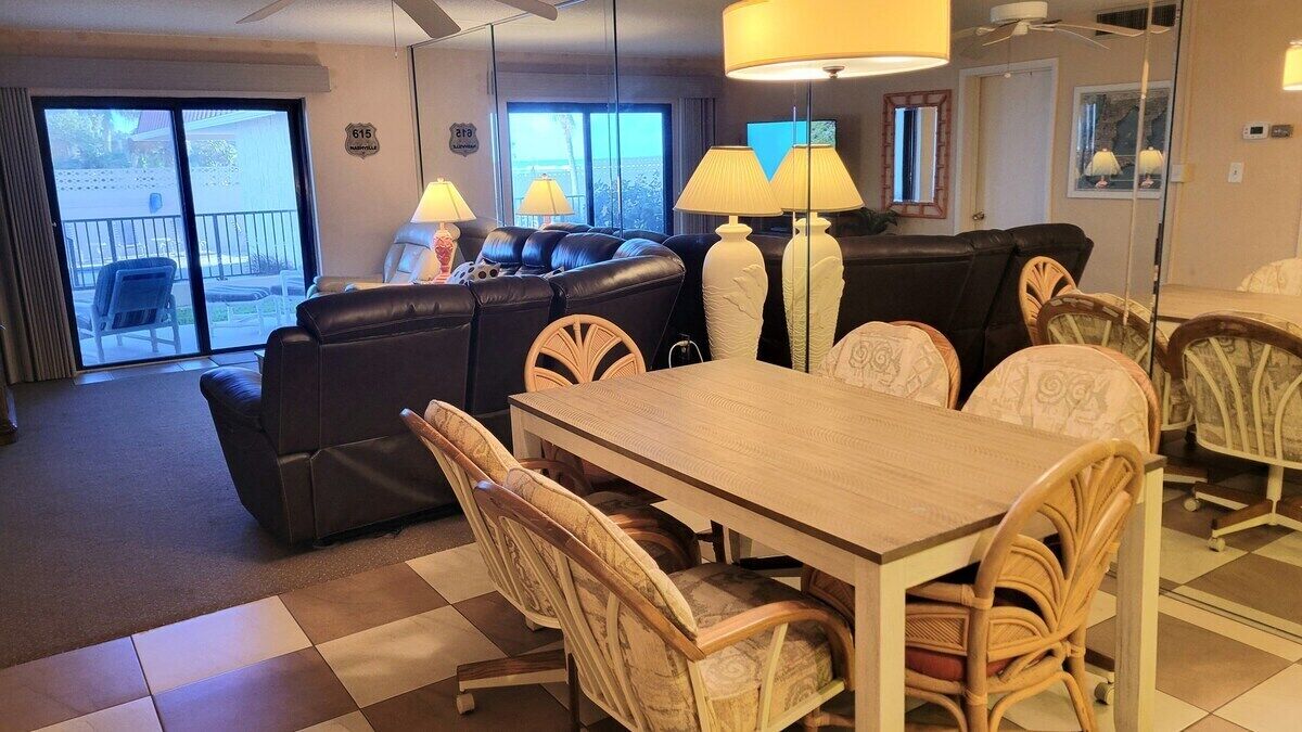 A hotel room with a dining area, a sofa, and a view of the outside.
