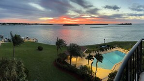 A pool area with a view of the water and sunset. - Magnificent Gulf View Condo 2 Bedroom Condo by RedAwning (Marco Island)