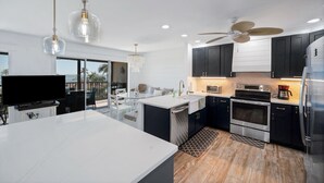 A modern kitchen with a central island, built-in appliances, and pendant lighting. - Magnificent Gulf View Condo 2 Bedroom Condo by RedAwning (Marco Island)