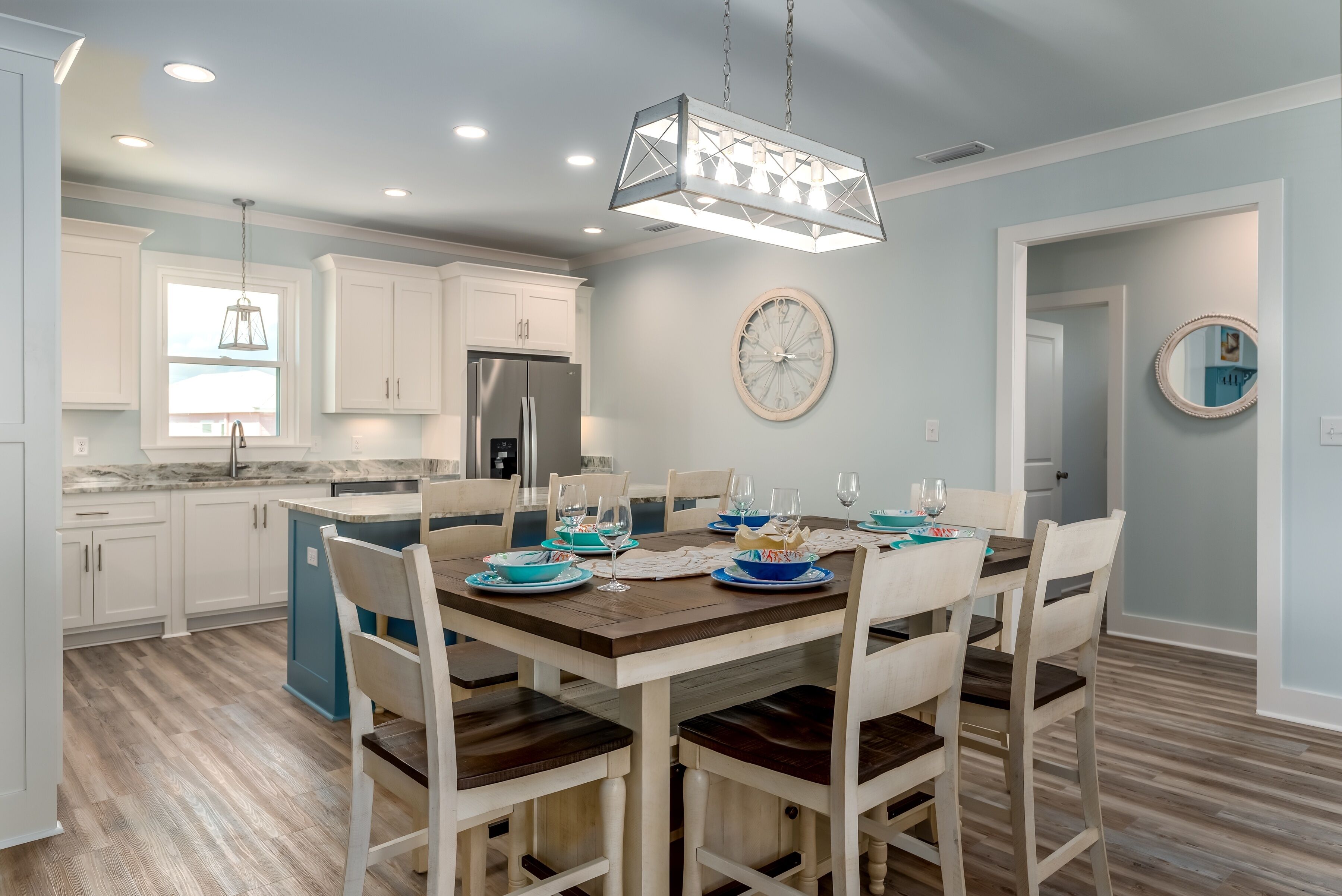 Una cocina moderna con armarios blancos, una isla central y un comedor con sillas de madera y una mesa para cuatro.