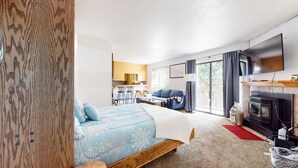 A modern hotel room with a bed, a sofa, a TV, a fireplace, and a balcony with a view. - La Vista Blanc #59 1 Bedroom Condo by RedAwning (Mammoth Lakes)
