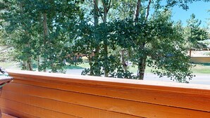A wooden bench with a view of trees and a building in the background.