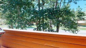 A wooden bench with a view of trees and a building in the background.