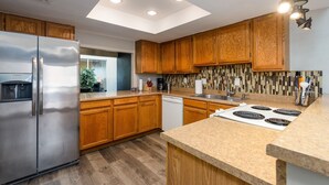 Une cuisine moderne avec des meubles en bois, un réfrigérateur en acier inoxydable, un lave-vaisselle, une cuisinière et une lucarne.