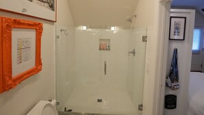 Une salle de bain équipée de toilettes, d’une douche et d’un espace de douche vitré.