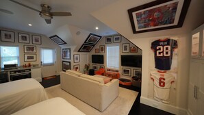 Une chambre d’hôtel équipée d’une kitchenette, d’un canapé, d’une télévision et décorée avec des objets de collection sur le thème du sport.