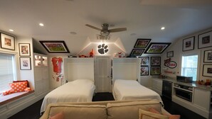 Une chambre avec deux lits, un canapé, un ventilateur de plafond et une kitchenette.