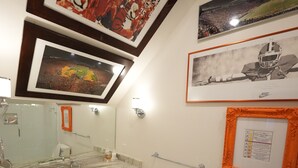 Une salle de bain avec un lavabo en marbre, un grand miroir et des tableaux encadrés accrochés au mur.