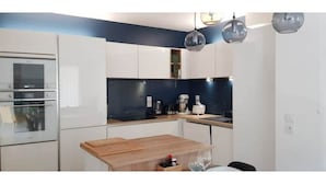 A modern kitchen with white cabinets, a wooden countertop, and a built-in oven.