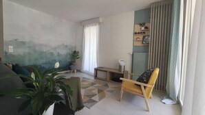 A living room with a sofa, a chair, a coffee table, and a painting on the wall.