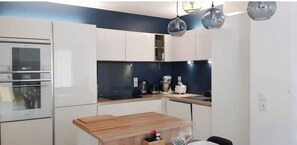 Una cocina moderna con armarios blancos, encimera de madera y horno empotrado.