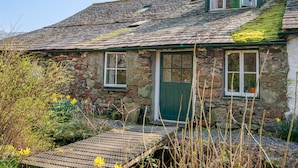A stone house with a green door, two windows, and a small balcony. - High Wallabarrow Farm Cottage -  Duddon Valley (Ulpha)