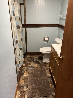 Ein Badezimmer mit Toilette, Waschbecken und einer Duschvorhang mit geometrischem Muster.