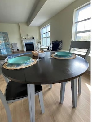 A dining area with a round table, two chairs, and a fireplace in the background. - Boston Area, Beautiful Sunsets & Free Parking (Braintree)