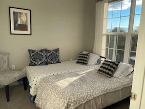 A bedroom with a bed, two pillows, a chair, and a window. - Boston Area, Beautiful Sunsets & Free Parking (Braintree)