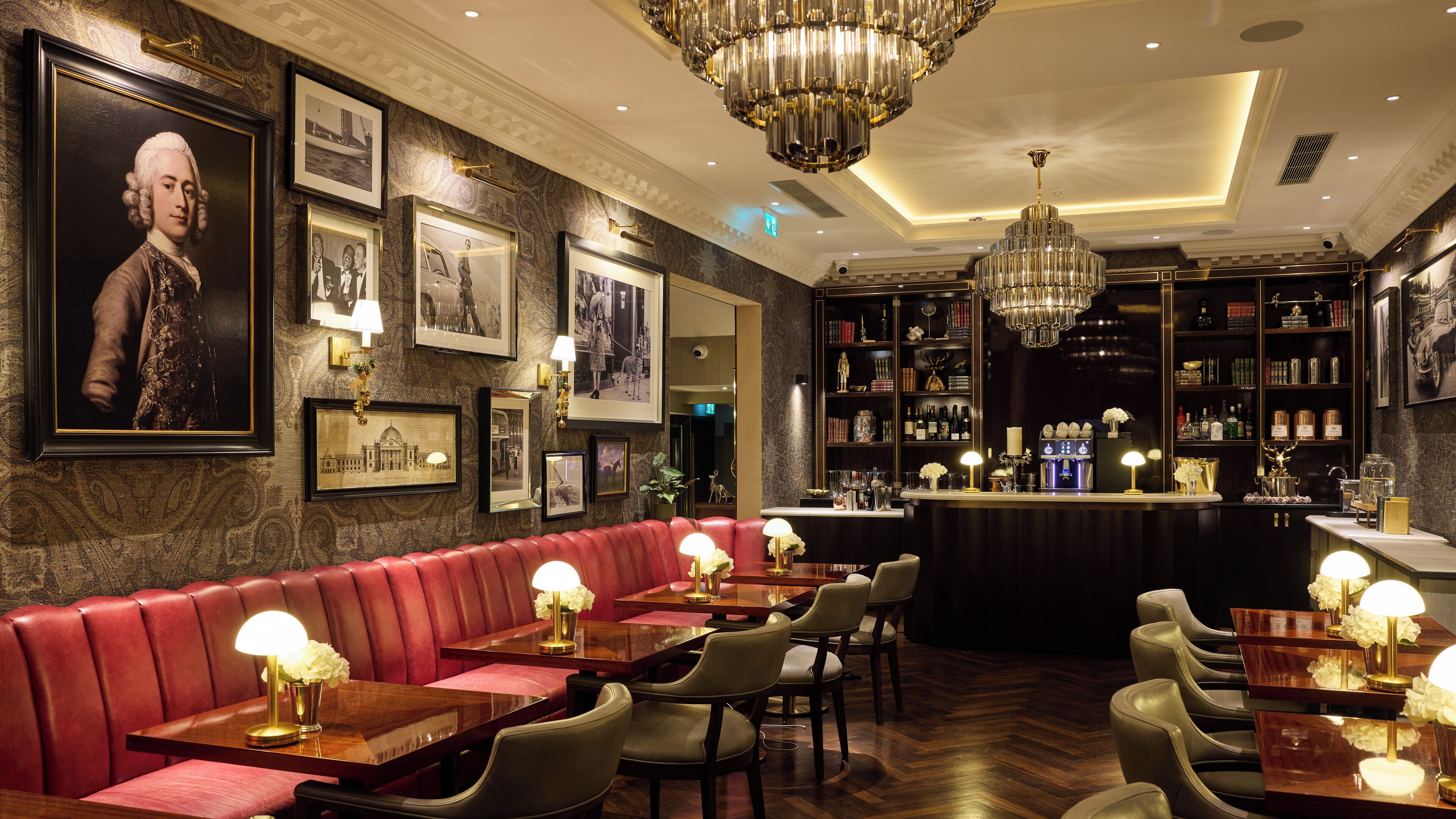A bar area with leather seating, framed pictures on the wall, and a well-stocked bar counter.