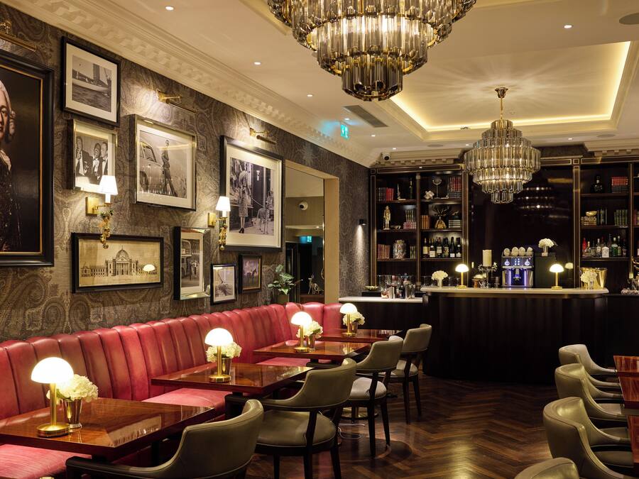 A bar area with leather seating, framed pictures on the wall, and a well-stocked bar counter.