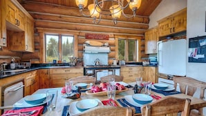 Una cucina in legno con un tavolo da pranzo apparecchiato per quattro persone, pensili in legno e un lampadario.