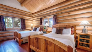 Camera da letto in una baita di legno con due letti di legno, comodini e una finestra con tende.