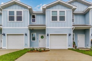 A row of light blue two-story houses with white garage doors and small front yards. - Elegant townhome + oversized luxury pool (Pensacola)