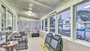 A cozy room with a sofa, a table, and a window with a view of houses. - East Tawas Cabin w/ Lake Huron Access & Views (East Tawas)
