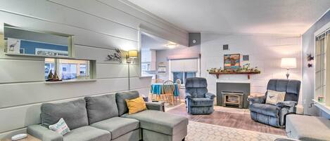 Una sala de estar moderna con un sofá seccional, dos sillones, una chimenea y un comedor con mesa y sillas.
