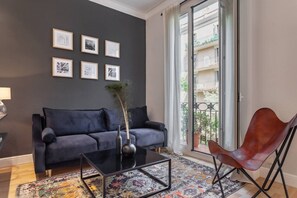A living room with a dark-colored sofa, a glass coffee table, a decorative vase, and a patterned rug. - Bright Design Flat near Sagrada Familia (Barcelona)