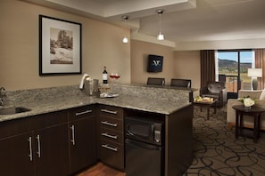 A kitchen with granite countertops, a microwave, and a sink. There is a dining area with a table and chairs, and a view of the outdoors. - Valhalla Hotel and Conference Centre (Thunder Bay)
