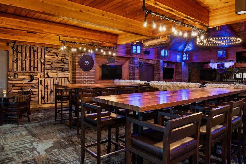 A rustic bar area with wooden furniture and a brick wall.