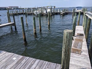 Un muelle de madera se adentra en aguas tranquilas, con varios barcos amarrados al final.