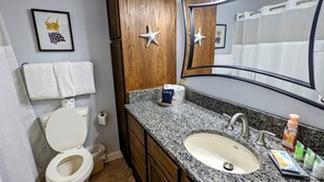 A bathroom with a toilet, sink, vanity, and a mirror. - Pirates Bay B205 - Waterfront Studio w/ Pool (Fort Walton Beach)